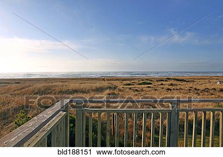 Stock Image - Balcony overlooking grassy field and beach. Fotosearch