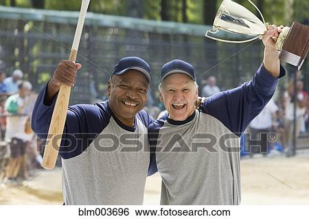 Stock Photograph - Baseball players holding bat and trophy. Fotosearch