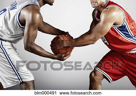 Stock Image - Basketball player trying to take basketball from opponent. Fotosearch
