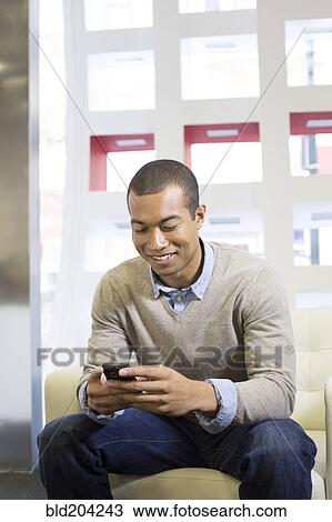 Stock Image - Black businessman using cell phone in office. Fotosearch