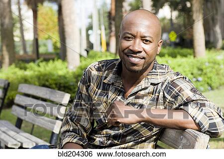 Stock Photograph - Black man smiling on park bench. Fotosearch