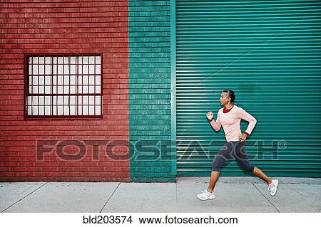 Picture - Black woman running on city street. Fotosearch