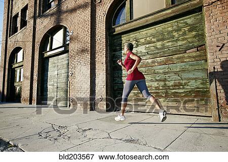 Stock Photo - Black woman running on city street. Fotosearch