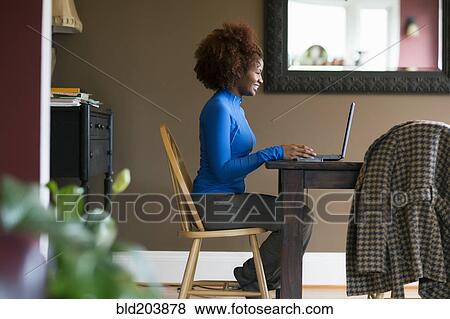 Stock Photo - Black woman using laptop at desk. Fotosearch