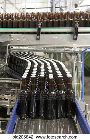Stock Image - Bottles on production line in bottling plant. Fotosearch