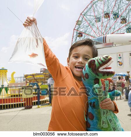 Stock Photograph - Boy at amusement park with stuffed dinosaur and goldfish. Fotosearch