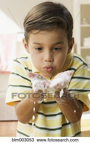 Stock Image - Boy blowing soap suds out of hands. Fotosearch