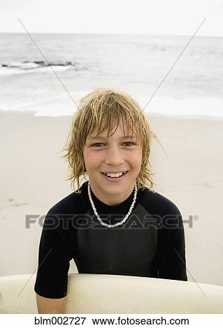 Stock Photo - Boy holding surfboard at beach. Fotosearch