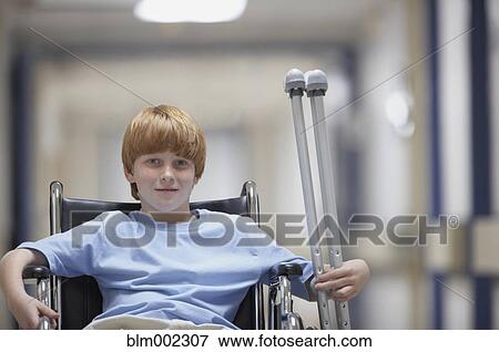 Stock Photo - Boy in wheelchair holding crutches. Fotosearch