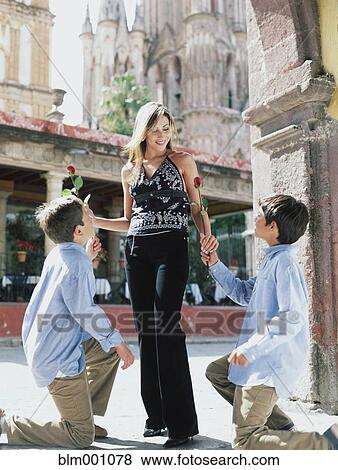 Boys kneeling and giving woman red roses View Large Photo Image Stock Photo - Boys kneeling and giving woman red roses. Fotosearch