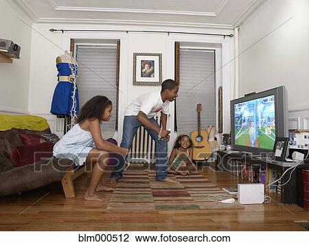 Stock Image - Brother and sister playing video game in living room. Fotosearch