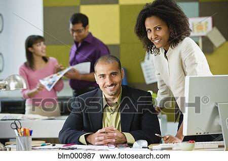 Stock Photo - Business people standing at office desk. Fotosearch