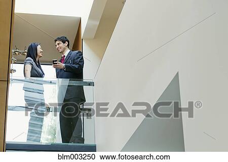 Stock Image - Business people talking in office hallway. Fotosearch