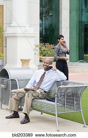 Stock Photo - Business people talking on cell phones outdoors. Fotosearch
