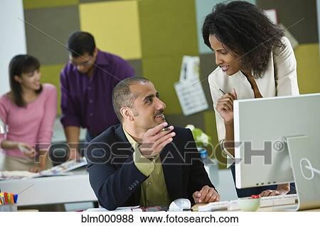 Stock Photo - Business people working together at desk. Fotosearch