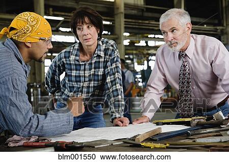 Businessman and warehouse workers looking at blueprints View Large Photo Image Stock Image - Businessman and warehouse workers looking at blueprints. Fotosearch