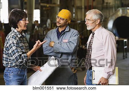 Stock Image - Businessman and warehouse workers with blueprints. Fotosearch