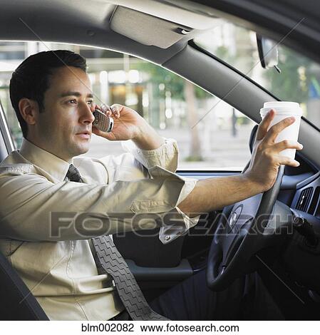 Stock Image - Businessman driving and talking on cell phone. Fotosearch