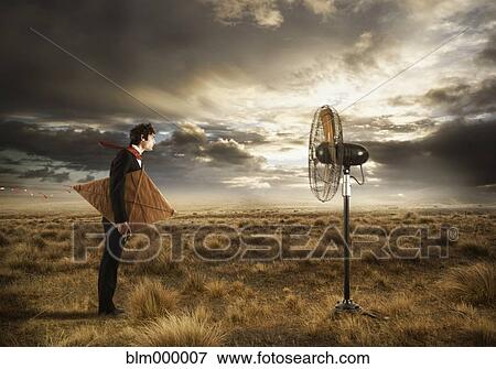 Stock Photo - Businessman holding kite and looking at fan. Fotosearch