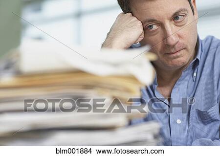 Picture - Businessman looking at stack of paperwork. Fotosearch