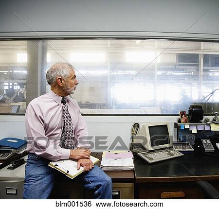 Stock Photograph - Businessman looking out window to warehouse. Fotosearch