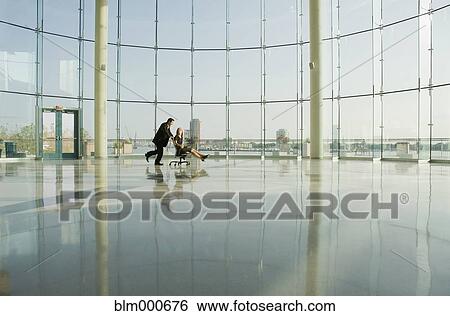 Businessman pushing businesswoman in rolling desk chair View Large Photo Image Stock Photograph - Businessman pushing businesswoman in rolling desk chair. Fotosearch