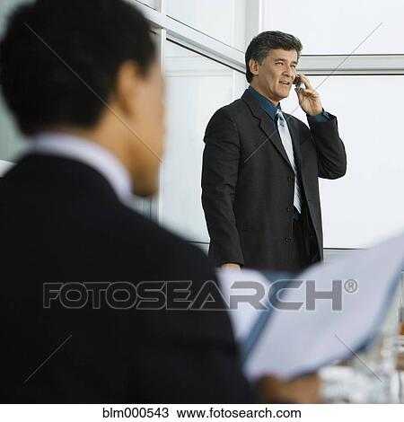 Stock Image - Businessman talking on cell phone in restaurant. Fotosearch