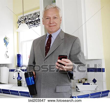 Businessman using cell phone in kitchen View Large Photo Image Stock Photo - Businessman using cell phone in kitchen. Fotosearch
