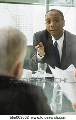 Businessmen discussing document in meeting View Large Photo Image Stock Image - Businessmen discussing document in meeting. Fotosearch