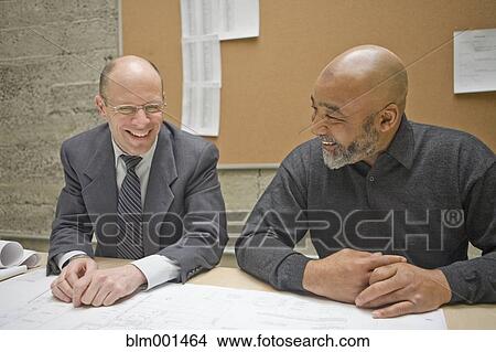 Picture - Businessmen reviewing blueprints in meeting. Fotosearch