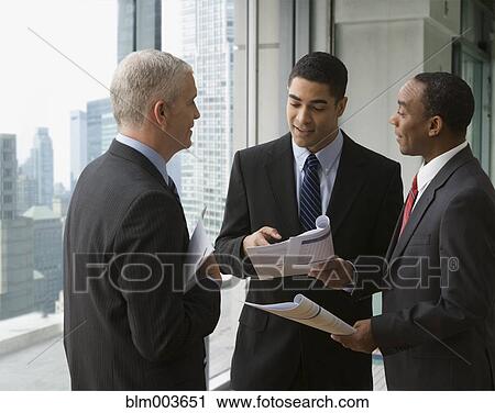 Businessmen reviewing document by office window View Large Photo Image Stock Image - Businessmen reviewing document by office window. Fotosearch