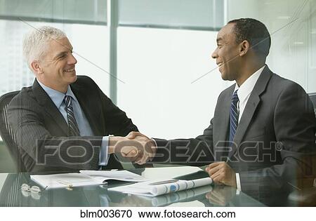 Businessmen shaking hands in office View Large Photo Image Stock Image - Businessmen shaking hands in office. Fotosearch