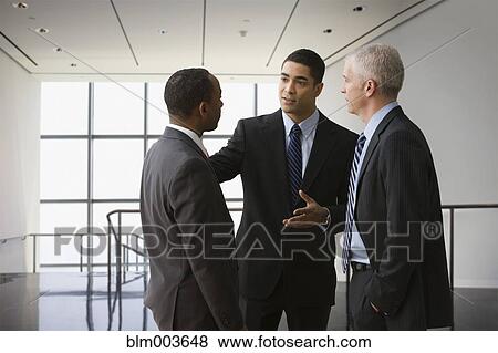 Stock Photo - Businessmen talking in corridor. Fotosearch