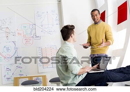 Picture - Businessmen talking in office. Fotosearch