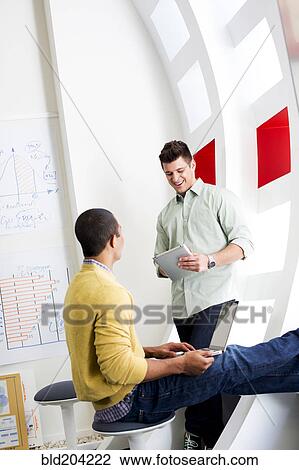 Stock Image - Businessmen talking in office. Fotosearch