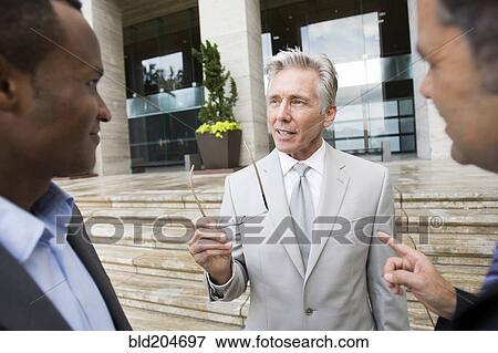 Businessmen talking on city street View Large Photo Image Stock Photo - Businessmen talking on city street. Fotosearch