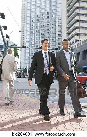 Stock Image - Businessmen walking together on city street. Fotosearch