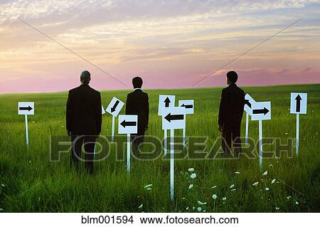 Picture - Businessmen with arrow signs in field. Fotosearch