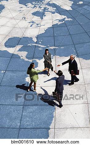 Stock Image - Businesspeople shaking hands on map of globe. Fotosearch