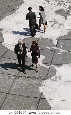 Businesspeople walking on map of globe View Large Photo Image Picture - Businesspeople walking on map of globe. Fotosearch
