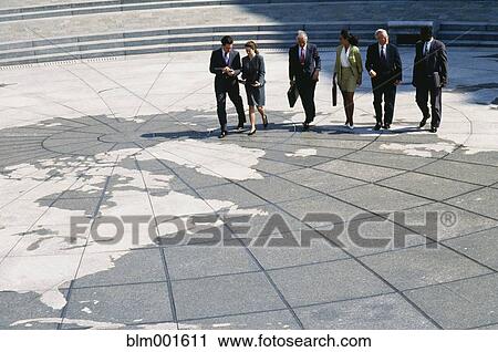 Stock Image - Businesspeople walking on map of globe. Fotosearch