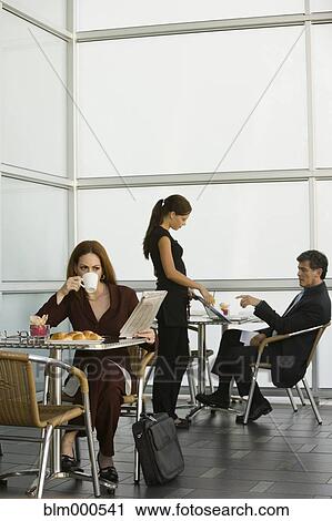 Stock Image - Businesswoman eating in restaurant. Fotosearch
