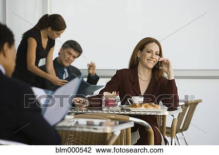 Stock Image - Businesswoman talking on cell phone in restaurant. Fotosearch