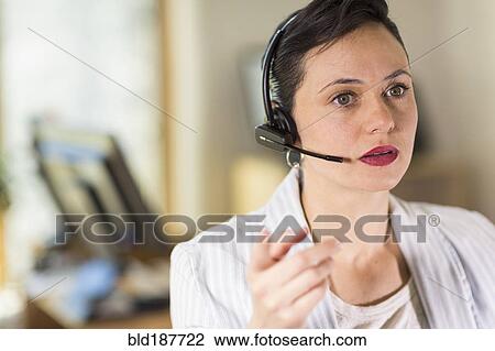 Businesswoman talking on headset in office View Large Photo Image Stock Image - Businesswoman talking on headset in office. Fotosearch