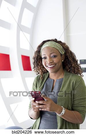 Stock Photograph - Businesswoman using cell phone in office. Fotosearch