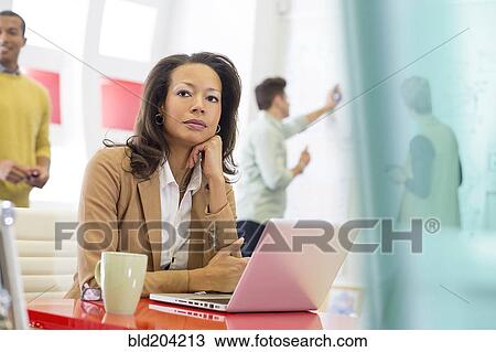 Stock Image - Businesswoman using laptop in office. Fotosearch
