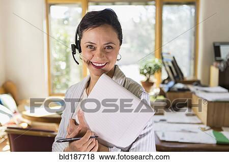 Businesswoman using notepad and headset in office View Large Photo Image Stock Photo - Businesswoman using notepad and headset in office. Fotosearch