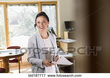 Stock Photo - Businesswoman wearing headset in office. Fotosearch