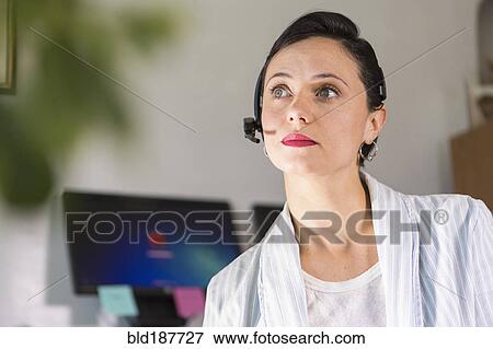 Stock Photo - Businesswoman wearing headset in office. Fotosearch