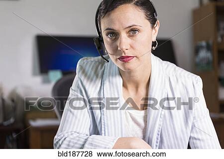 Businesswoman wearing headset in office View Large Photo Image Stock Photo - Businesswoman wearing headset in office. Fotosearch